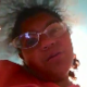 A black girl with glasses video-records herself taking a shit while sitting on a toilet and showing us her facial expressions during the event. Poop sounds are clearly heard.